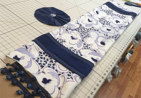 Custom drapes in progress of blue flowered fabric with dark blue accent material, on worktable