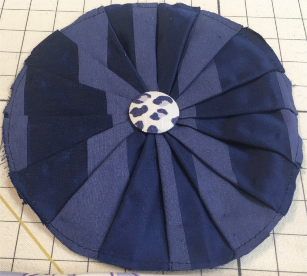 Cushion in two-toned blue pleated fabric with button in center